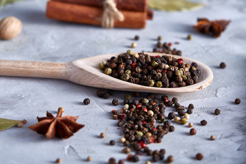 Peppercorns in wooden spoon with clipping path on white textured background, close-up, selective focus.