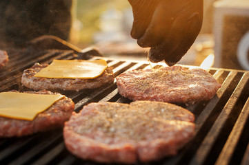 Preparing beef cutlet with spices for burgers  on the grill. Street food. Picnic on the street