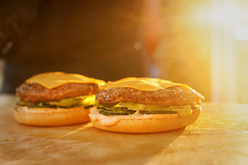 Part of a burger on a wooden board. Street fast food. Sunset light.