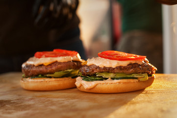 Part of a burger on a wooden board. Street fast food. Sunset light.