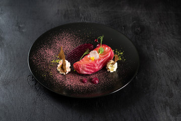 Red fish salmon dish with sauce on black background