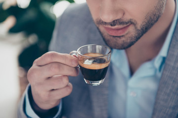 Cropped close up half face portrait of stylish attractive man holding small glass with espresso...