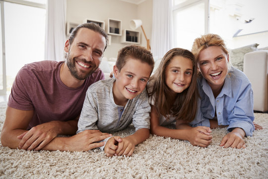 Portrait Of Family Lying On Rug In Lounge At Home