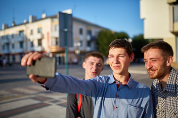 Portrait of a group of smiling and grin friends on summer holiday, making selfie on camera on urban background.
