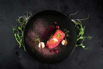 Red fish salmon dish with sauce on black background