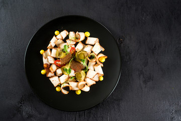 dish of many pieces of lard with vegetables on black background