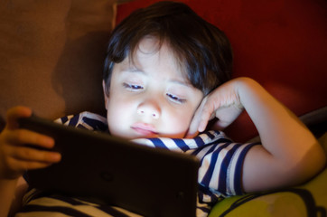 A young boy with a tablet PC in the evening.