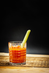 juicy red drink bloody mary with a piece of green celery on a wooden table