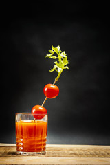 juicy red bloody mary drink with tomatoes on a stick on a wooden table © superelaks