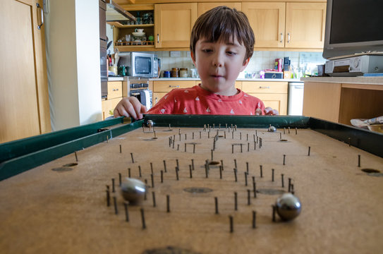A young boy plays with an old bagatelle game.