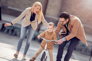 Mom and dad teaching they son to ride a bike