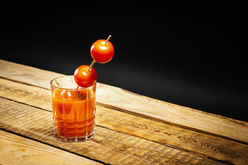 juicy red bloody mary drink with tomatoes on a stick on a wooden table