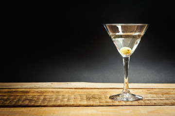 delicious martini drink with olive in a glass on a wooden table