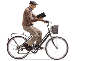 Obraz premium Elderly man riding a bicycle and reading a book