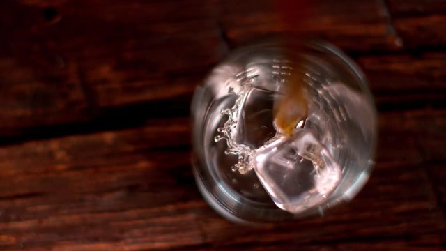 Super slow motion of pouring whiskey into glass, top view. Filmed on cinema slow motion camera, 1000fps