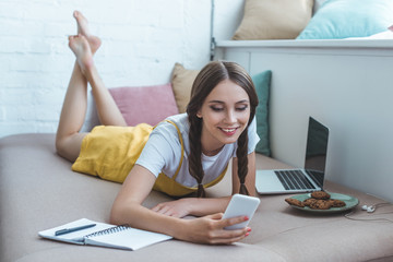 Obraz premium happy student with earphones and laptop writing in copybook