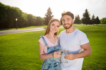 Harmony inspiration delight pleasure concept! Portrait of stylish attractive couple drinking sparkling wine beverage over green grass forest outside looking at camera enjoying romantic date together