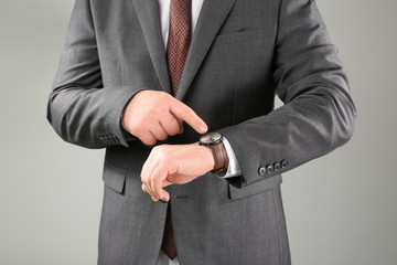 Man with wrist watch against grey background. Time management concept
