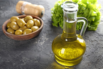 Glass jug with fresh olive oil on table