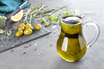 Glass jug with fresh olive oil on table