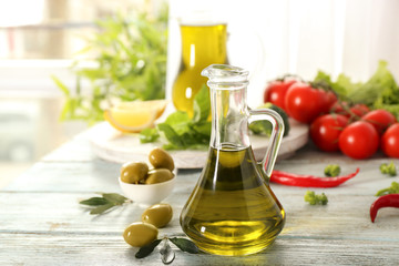 Glass jug with fresh olive oil on wooden table