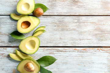 Composition with ripe avocados on light wooden background
