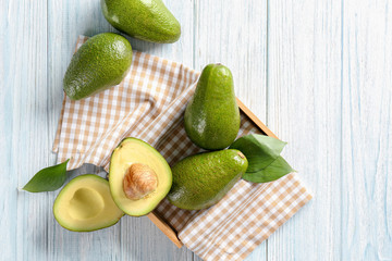 Composition with ripe avocados on light wooden background