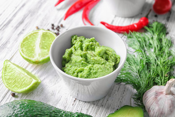 Bowl with tasty guacamole on wooden table