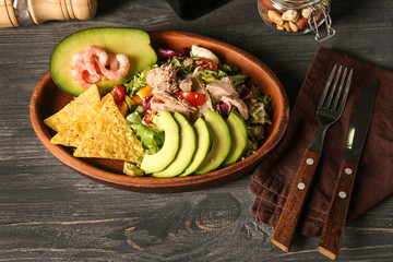 Plate of tasty salad with ripe avocado on wooden table
