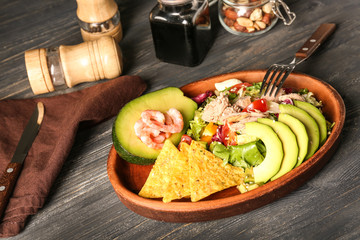 Fototapeta na wymiar Plate of tasty salad with ripe avocado on wooden table