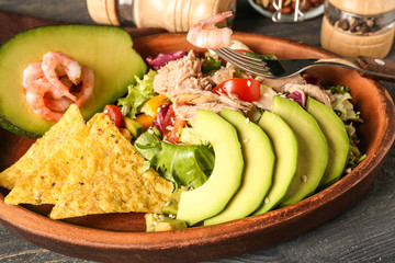 Plate of tasty salad with ripe avocado on wooden table, closeup