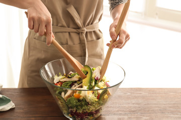 Woman preparing tasty salad with ripe avocado at table