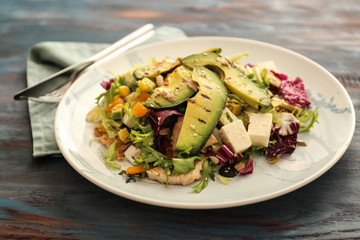Plate of tasty salad with ripe avocado on wooden table