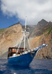 Old boat and active volcano Batu Tara, Indonesia.