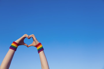 Gay pride concept. Hand making a heart sign with gay pride LGBT rainbow flag wristband