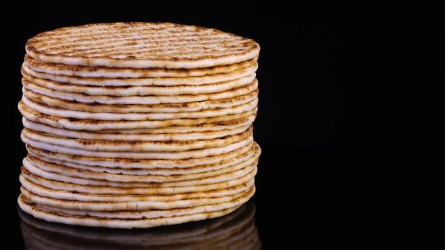 Tasty flat bread (lavash, pita, chapati, scone) rotating in 4K. Traditional food on black background with free space for text.
