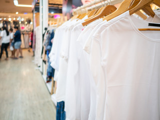 White shirt women's dresses on hangers in a retail shop clothing store. Fashion and shopping concept