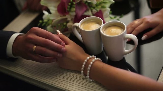 Wedding couple. Two Cups Of Coffee And Groomy Stroking Hands Of The Bride