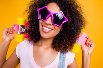 Head shot portrait of pretty cool chick in summer glasses star shape holding pink skate board on...