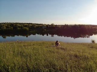 A girl is posing near a lake on a hill. aerial photography.