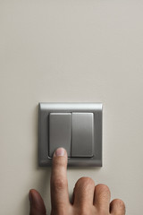 light switch on the wall and a man's hand