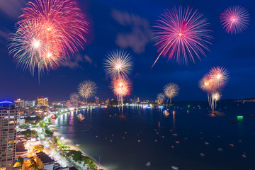 Fantastic and colorful fireworks over the sea and city with blue twilight sky background and city...