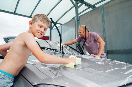 Boy helps his father to wash a car, simply home work child help