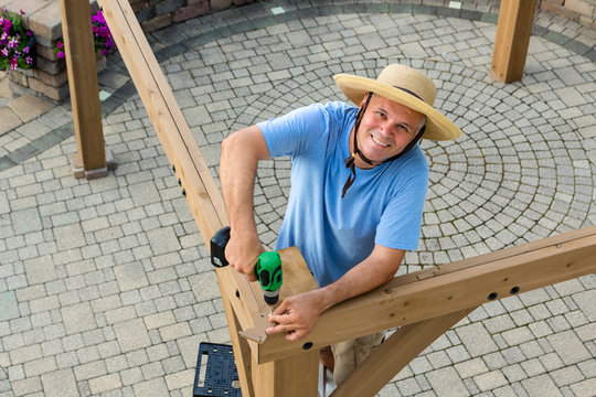 Happy Confident Man Erecting A New Outdoor Gazebo