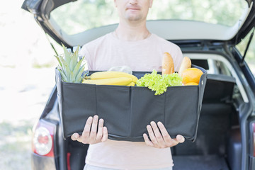 Man holds in his hands big black bag basket full of products