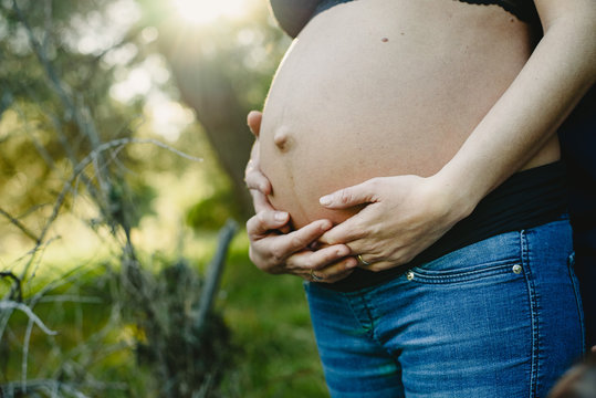 Belly of pregnant woman walking by in nature