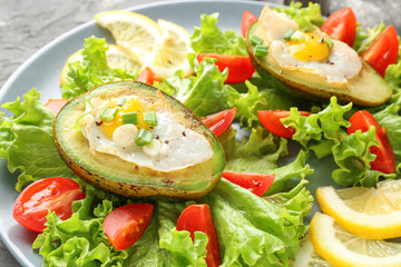 Eggs baked in avocado and fresh vegetables on plate, closeup