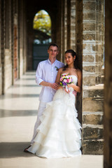 Wedding couple standing in the gallery of the Catholic Church. The groom hugs the bride.