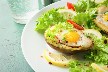 Eggs baked in avocado and fresh vegetables on plate, closeup