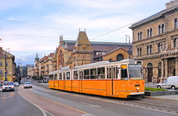 Fototapeta na wymiar Budapest street with old yellow tram and classic buildings and architecture with city traffic. Hungary 